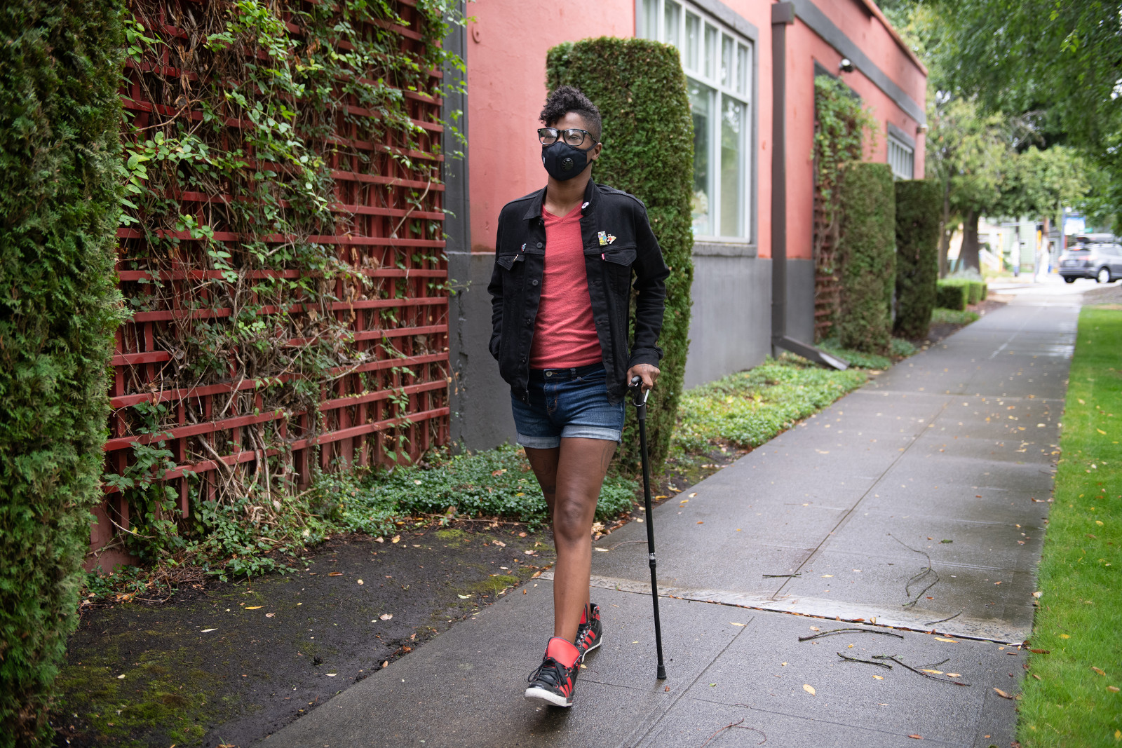 Foto einer Person, die mit einem Gehstock auf einem Gehweg geht.